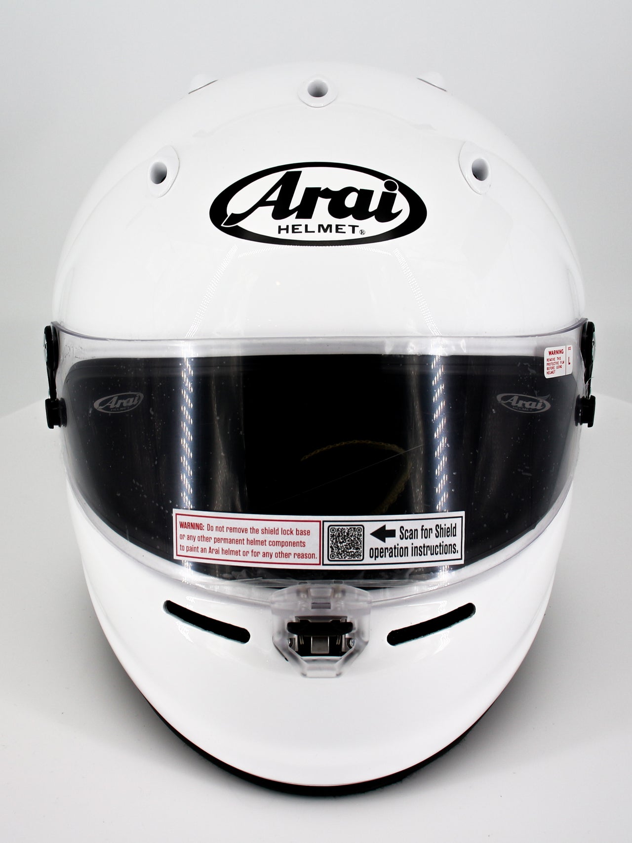 A white Arai full-face racing helmet with a clear visor and black logo on a light gray background.