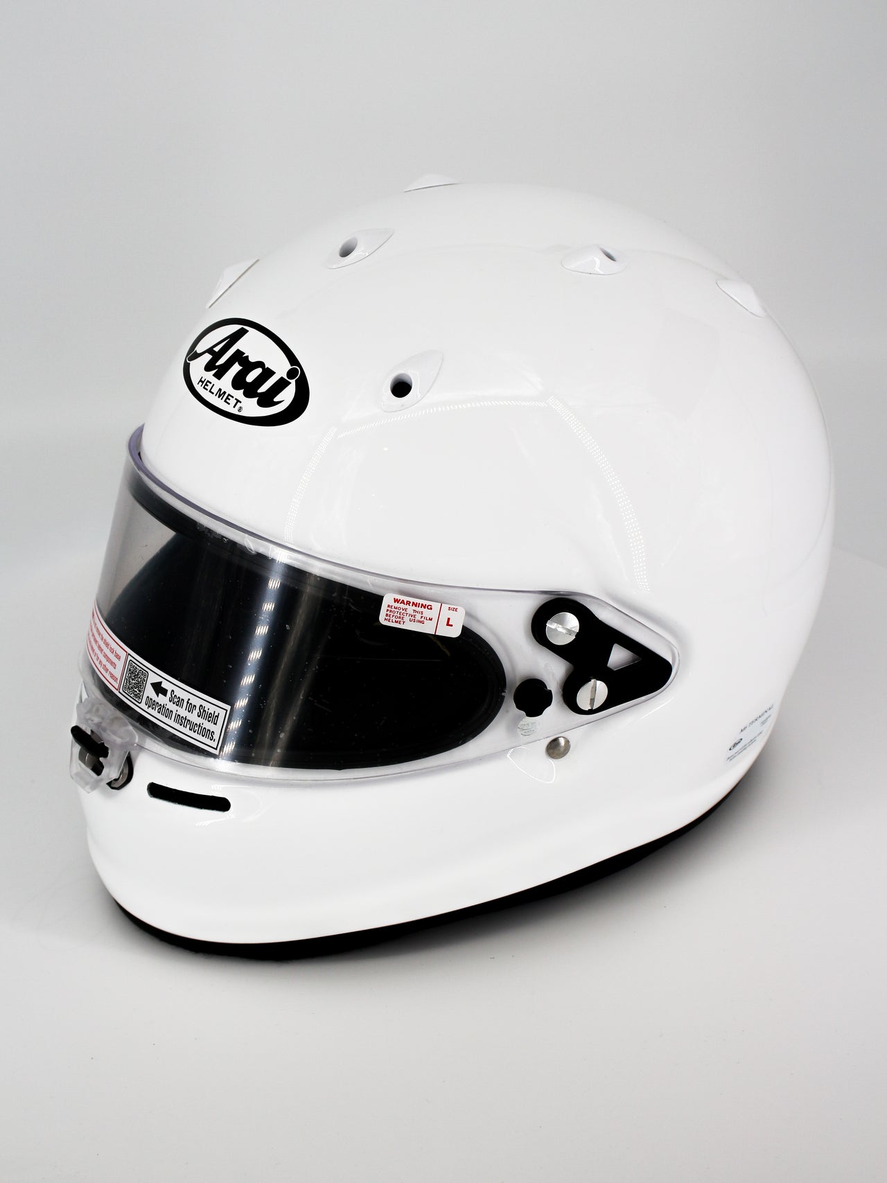 A white Arai full-face racing helmet with a clear visor, photographed on a light gray studio background.