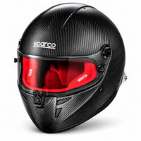 Thumbnail for Sparco Stealth RF Carbon SA2025 racing helmet in three-quarter front view, featuring an exposed carbon fiber shell, red fire-resistant interior padding, clear visor, central locking mechanism, and HANS anchors.